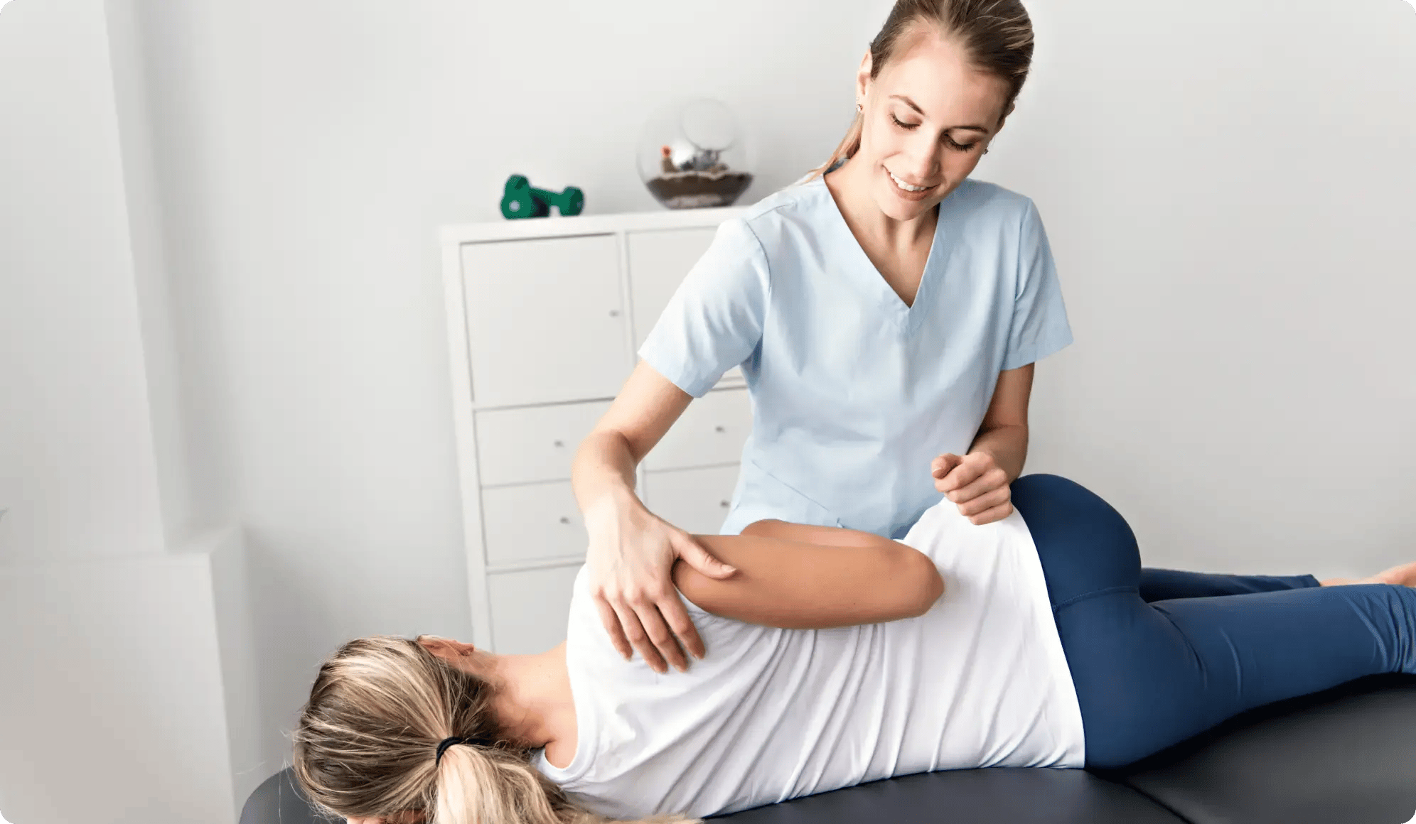 A chiropractor helps a woman crack her back while lying down.