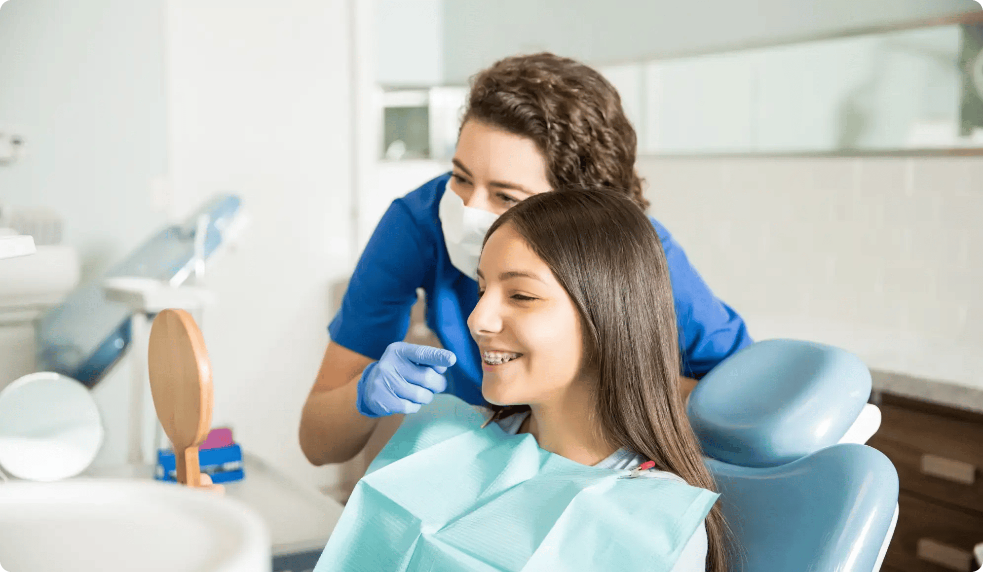 An orthodontist pointing out the changes in a young girl's teeth with braces.
